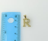 A delicate gold plated pendant featuring a twisted letter "R" shape. 
A small, intricately designed twisted gold plated